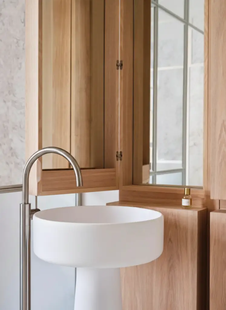 Contemporary bathroom with round white bathtub and circular natural wood element